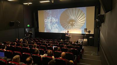 Chris presenting with an image of the QPS-SAR satellite on the screen